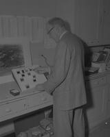 A picture of a Mankato State College geography professor looking at a set of negatives, 1960s.